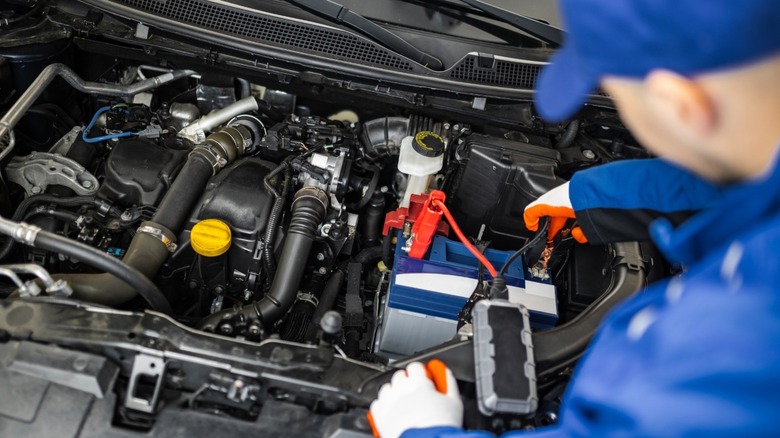 A mechanic using portable jump starter on car