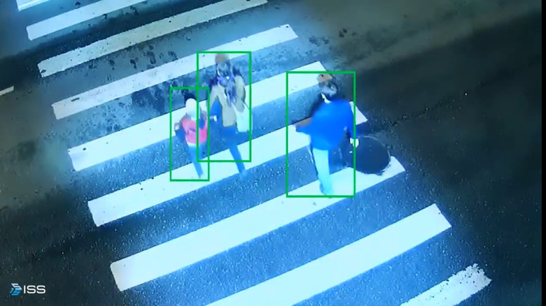 A screenshot from its SecurOS Soffit demonstration video showing the AI following pedestrians as they cross the street with traffic on a roadway at night.