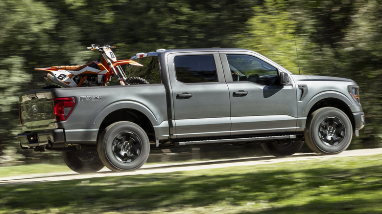 Side view of a 2024 Ford F-150 hauling a motorcycle in its aluminum bed