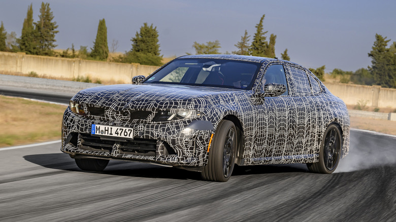Front 3/4 view of the camouflaged 2027 BMW M350 xDrive drifting.