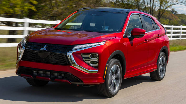 Mitsubishi Eclipse Cross driving on a road next to trees and a white fence