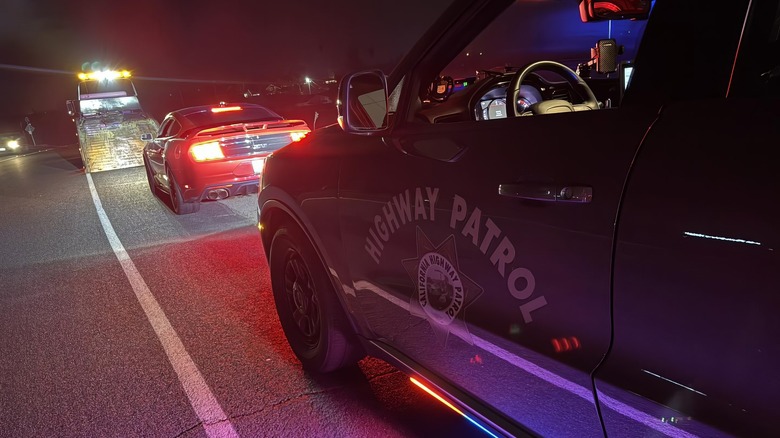 A red Ford Mustang GT being loaded onto a flatbed in front of a CHP patrol vehicle