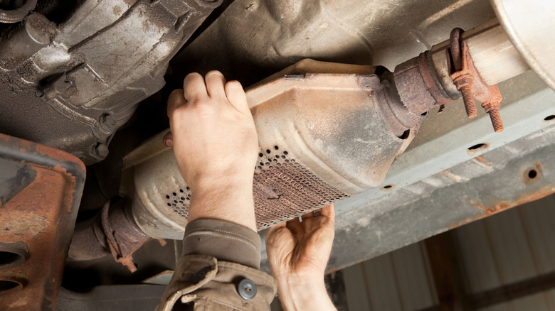 A catalytic converter being removed from underneath a car