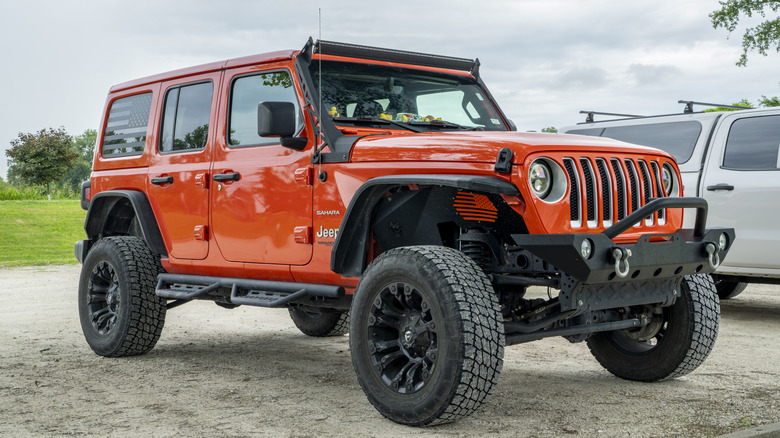 An orangish Jeep Wrangler parked successful a ungraded parking lot.