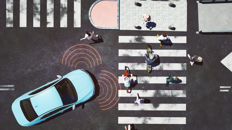 An autonomous vehicle approaches a complex intersection with people on bikes and walking about.
