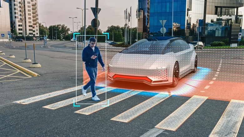 A 3D rendering of an autonomous vehicle approaching a crosswalk in a city area that stops for a man walking across the way looking at his cell phone.