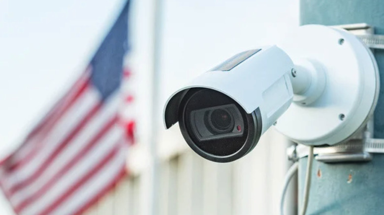 A close up of one of Leonardo Company's ALPR devices attached to a pole, with an American flag waving in the background.