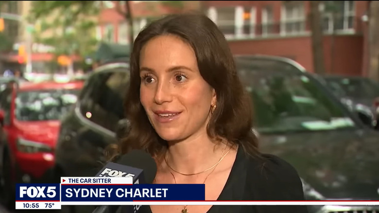 a screenshot of a news interview showing Sydney speaking into a mic
