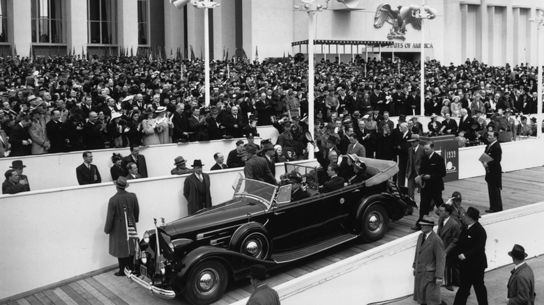 From his car drawn up at the entrance, President Roosevelt (1882 - 1945) waves to the crowds at the opening of the World Fair, New York.