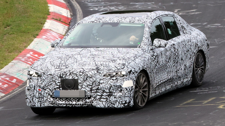 A front three-quarters view of a camouflaged Mercedes E-Class EV on the N&uuml;rburgring