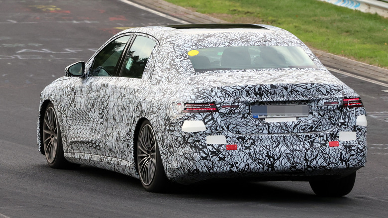 Rear 3/4 view of a camouflaged Mercedes E-Class EV on the Nürburgring