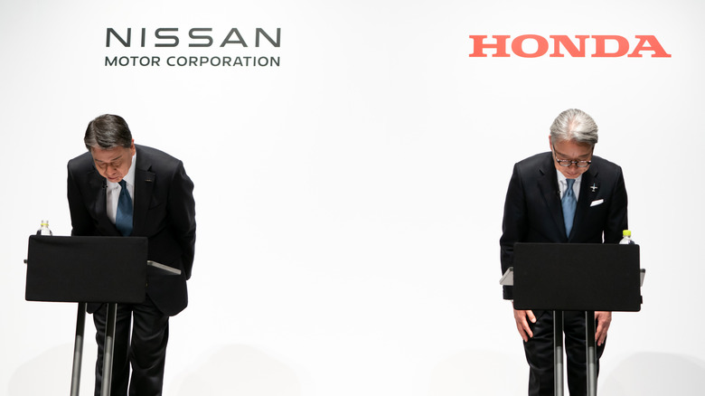 Nissan and Honda executives seen bowing on stage.