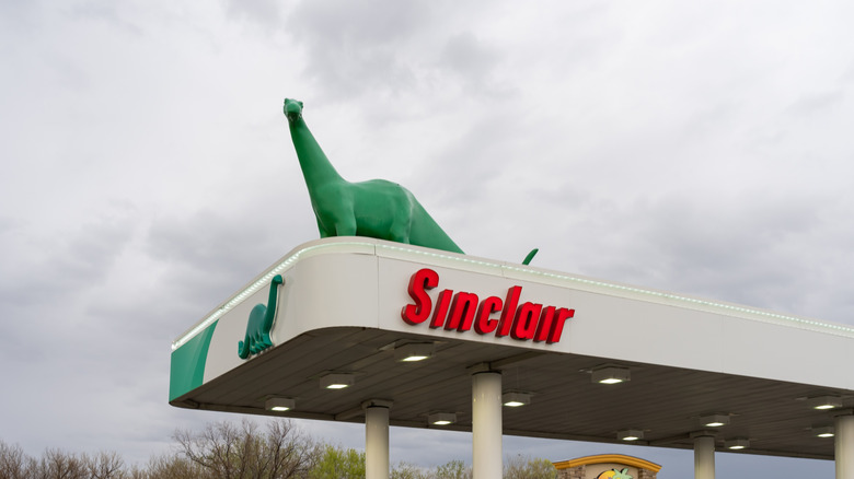 A Sinclair gas station with a green dinosaur mascot above the pumps