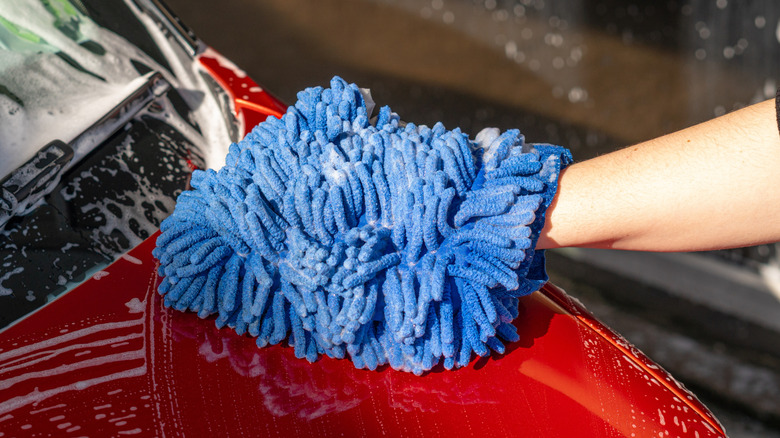 Car owner washing a car using a chenille microfiber was mitt