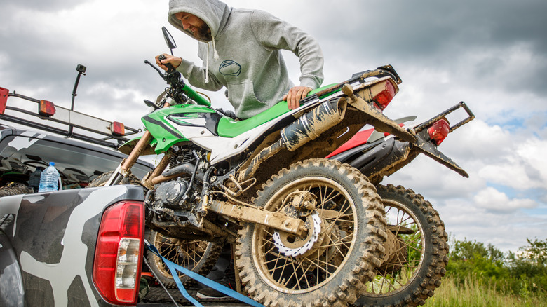 A man strapping down dirt bikes to a truck bed