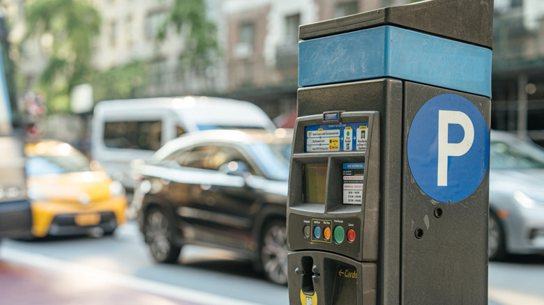 A closeup of a parking meter on a busy street