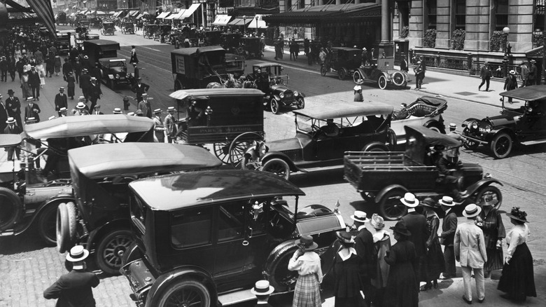 A black-and-white image of a busy street packed with old cars