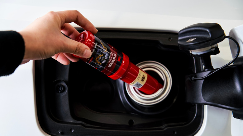 Person adding fuel additive to fuel tank