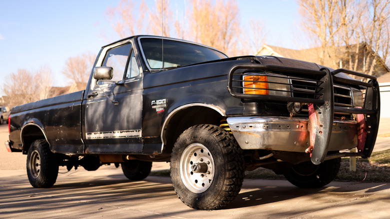 A faded black eighth-gen Ford F-150 parked on the street