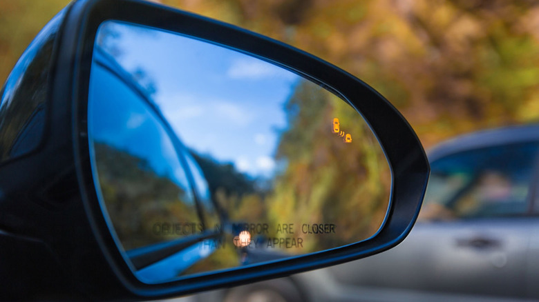 Close-up of a vehicle's wing mirror displaying the blind spot assist feature in action.
