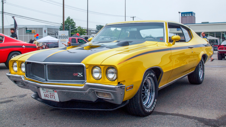 A yellow 1970 Buick GSX muscle car parked at a car show