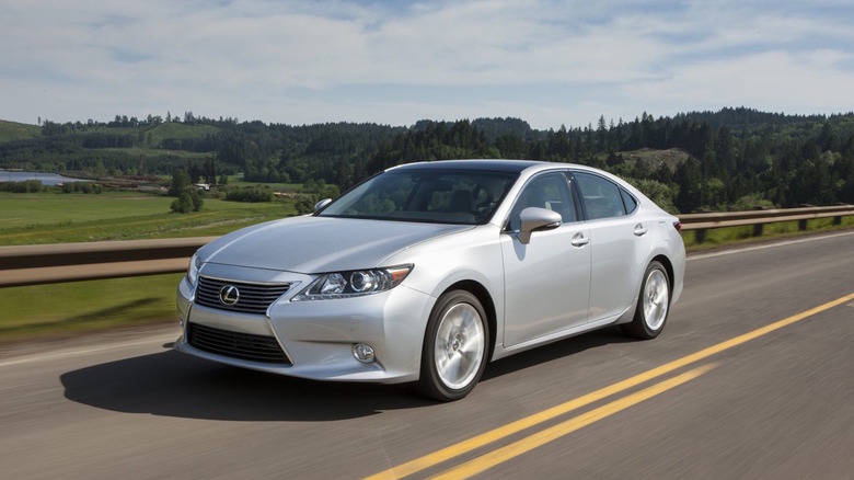 A silver Lexus in motion on a two-lane roadway.