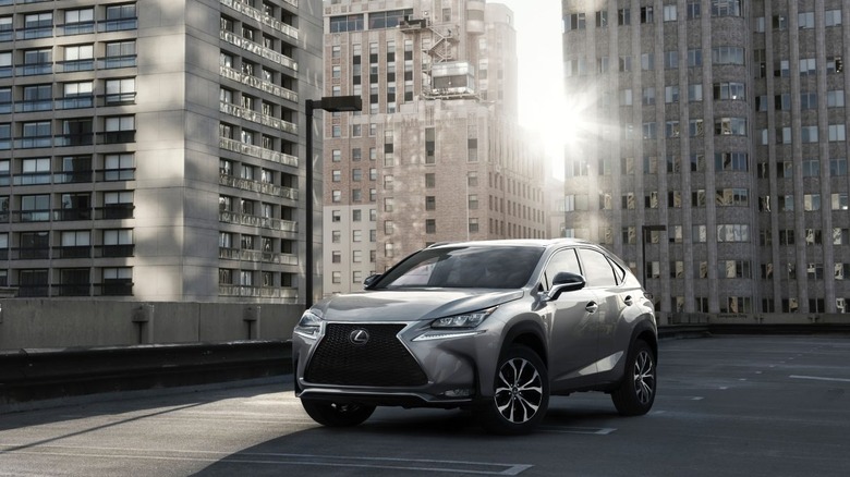 A silver 2015 Lexus NX 200t in front of tall buildings in an urban area.