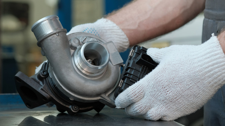 A mechanic pinch achromatic gloves connected holds a turbocharger