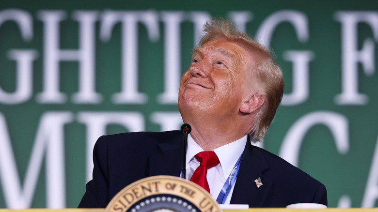 Donald Trump behind a podium looking up at the sky