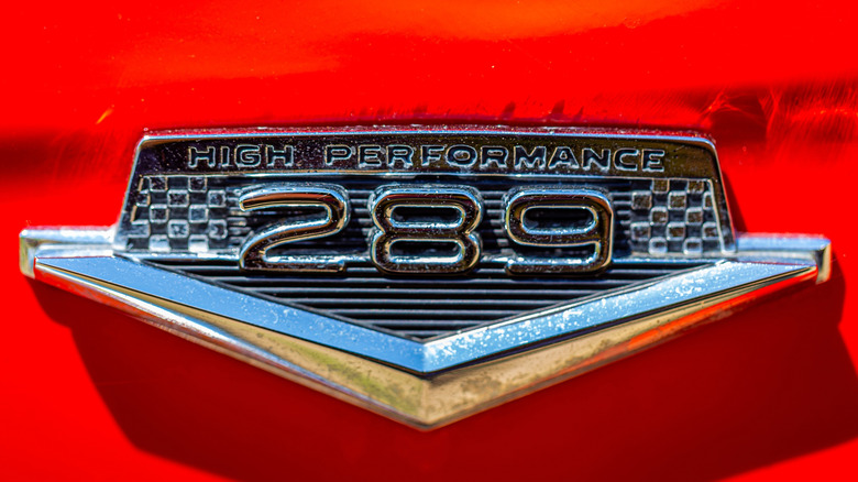 A chrome K-code Mustang fender badge on a red background