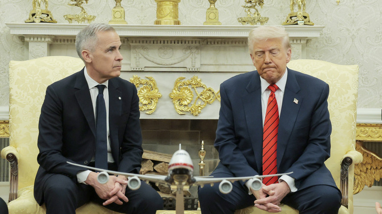 Trump looking rather disappointed or distracted with his model plane while sitting with Carney during talks at the White House in the Oval Office.