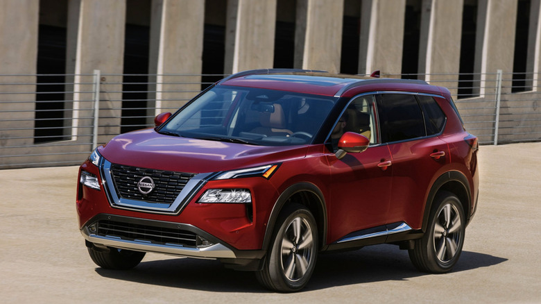A red 2021 Nissan Rogue driving down the street