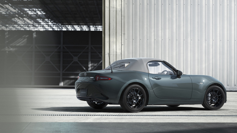 A 2026 Mazda MX-5 in an industrial setting, wearing the new Zinc Green Metallic color.