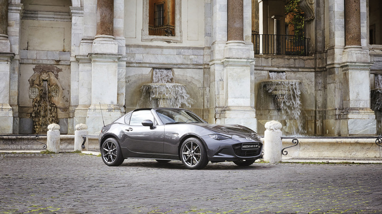 A grey Mazda MX-5 RF in the front of an ornate European building.