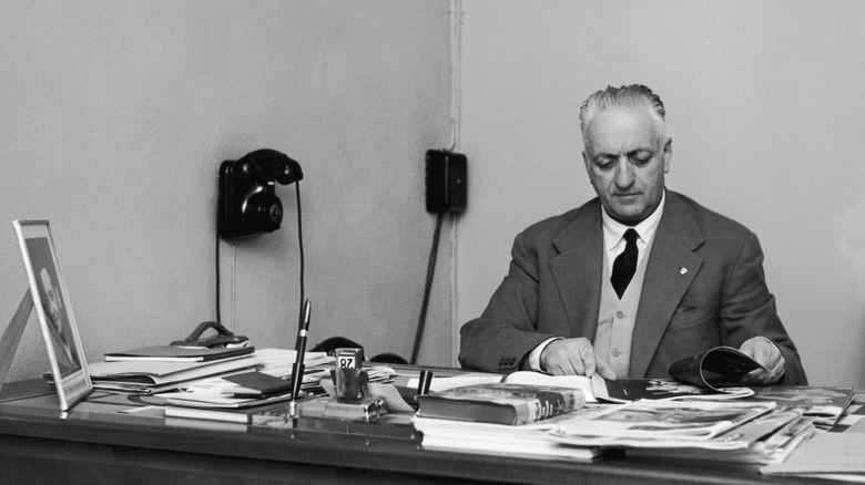 Enzo Ferrari reads magazines on his cluttered desk