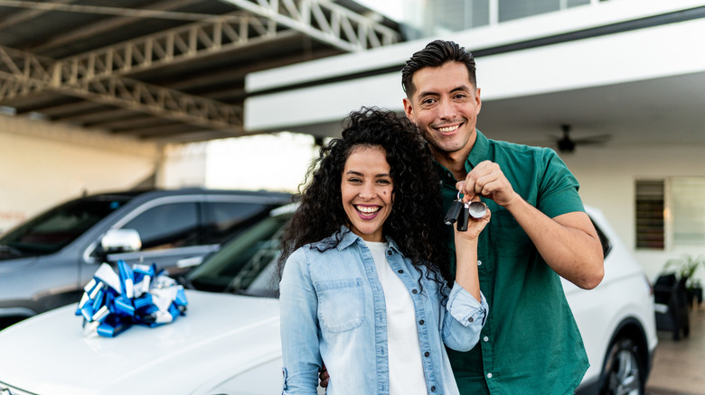 Stock image of couple holding keys to new car.