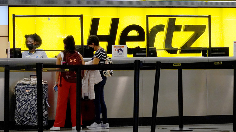 MIAMI, FLORIDA - OCTOBER 25: People rent cars at a Hertz car rental counter in the Miami International Airport on October 25, 2021 in Miami, Florida. Hertz announced that it ordered 100,000 Teslas as the company is emerging from bankruptcy.