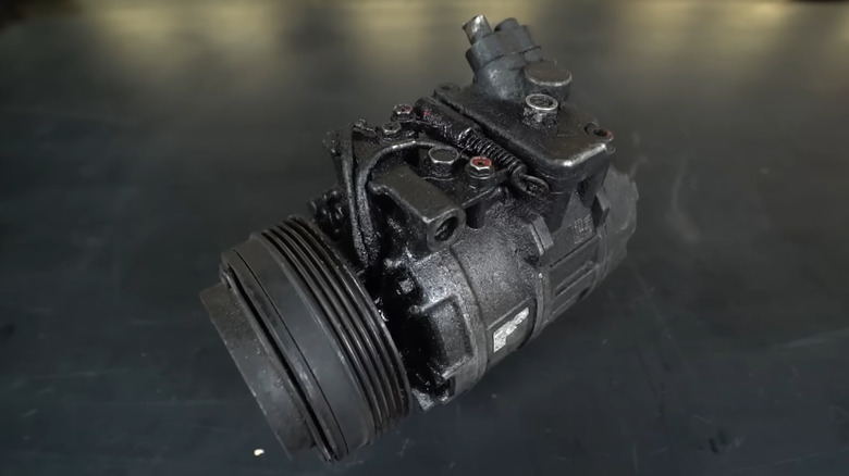 An old AC compressor covered in oily residue
