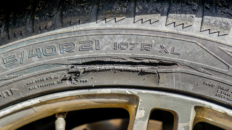 Close up view of a large, deep cut on the sidewall of a passenger car tire