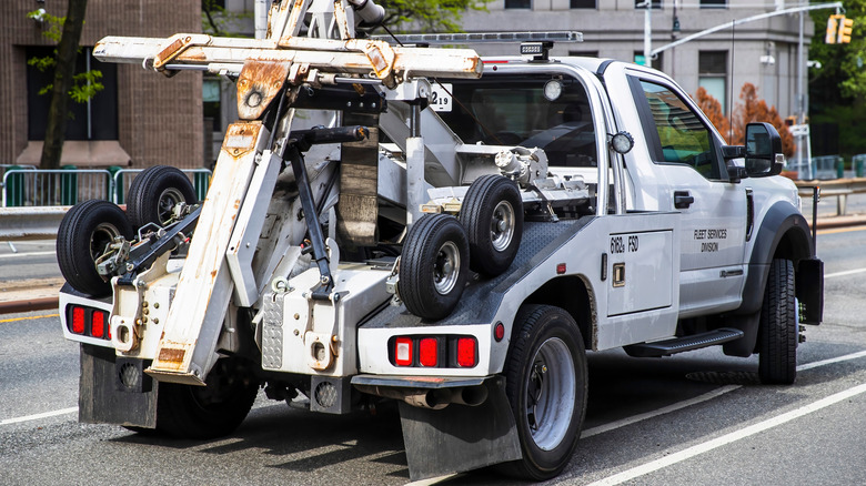 Rear 3/4 view of a white tow truck on a city street