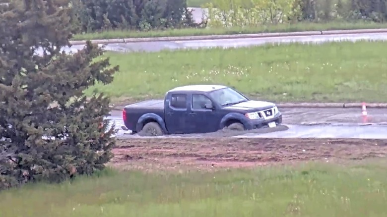 Side view of a Nissan Frontier stuck in wet concrete after ignoring "road closed" signs