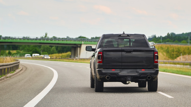 A black pickup truck driving on a quiet highway