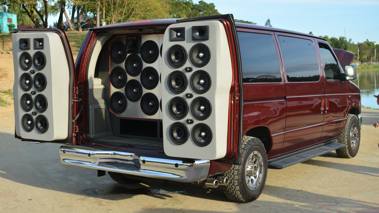 A red van with its rear doors open showcasing an aftermarket stereo setup.