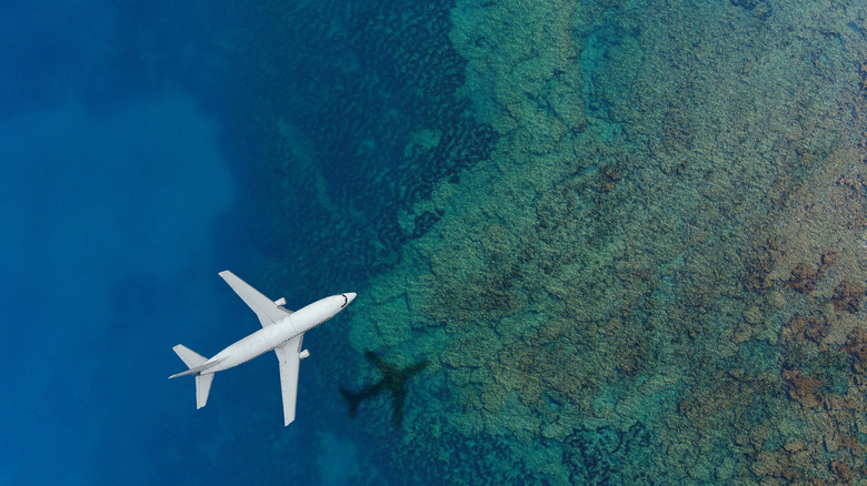 An artist's rendering of a passenger jet flying over a coral reef
