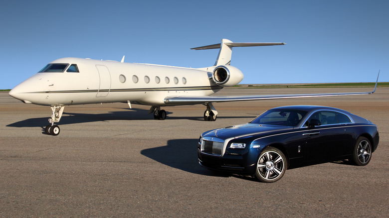 A private jet constructed with rivets next to a luxury automobile constructed with welds.