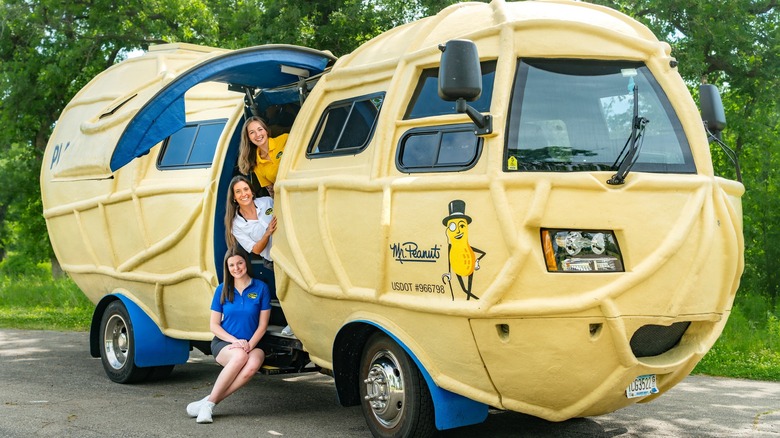 The NUTmobile with its side door open and the three current Peanutters sitting on the stairs up into the cab