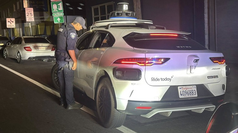 A San Bruno, California, police officer looks into a driverless Waymo robotaxi