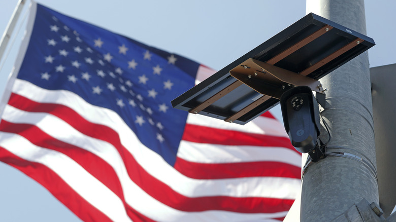 An American flag flies behind a Flock Safety camera tmounted to a light pole on August 03, 2026 in Burbank, California.