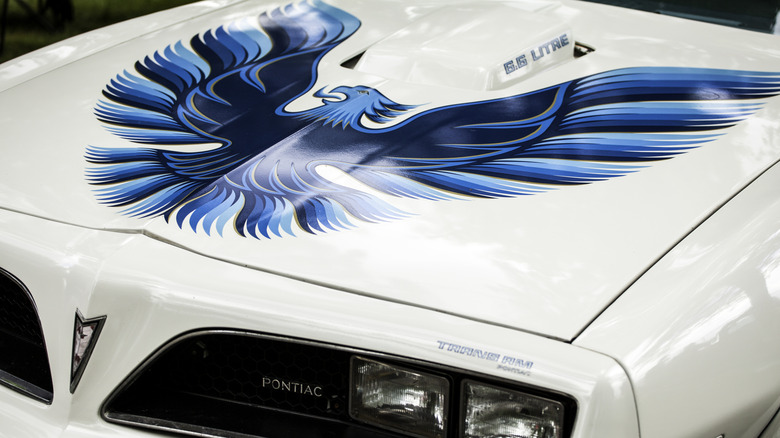 A white Pontiad Trans-Am car with bird decal on hood