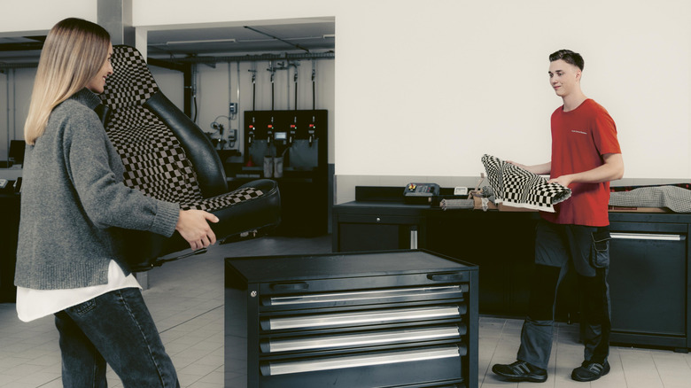 Two people holding a Porsche seat and a swatch of fabric